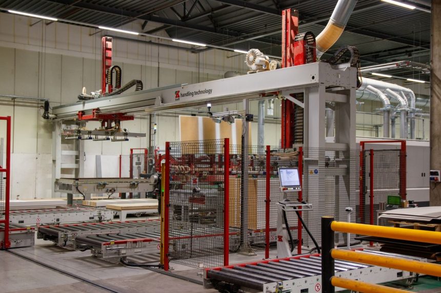 Braço robótico ao lado de máquinas em uma moderna instalação de manufatura industrial.